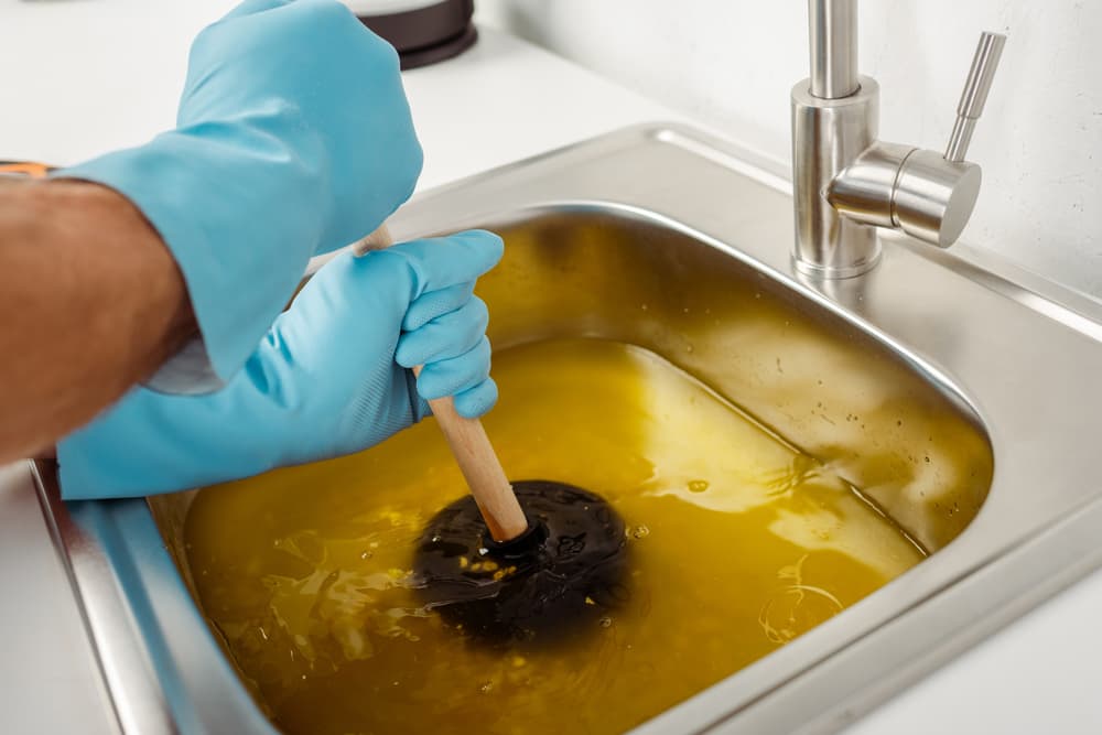 plumber clearing clogged kitchen sink